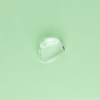 Drop of transparent face and body cream on a green background