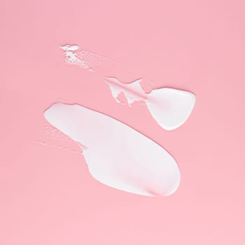 Smear of white cream for face and body on a pink background