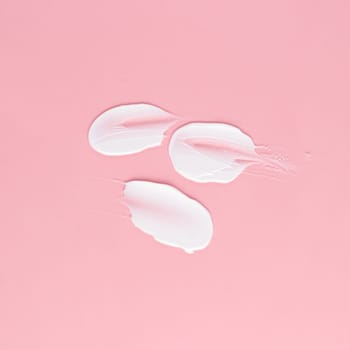 Smear of white cream for face and body on a pink background