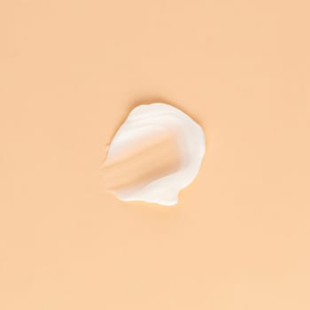 Smear of white cream for face and body on a brown background