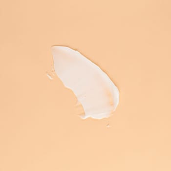 Smear of white cream for face and body on a brown background