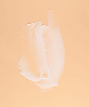 Smear of white cream for face and body on a brown background