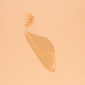 Smear of brown cream for face and body on a sand color background