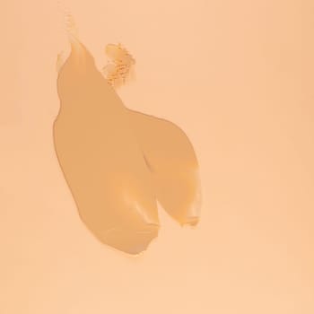 Smear of brown cream for face and body on a sand color background