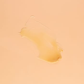 Smear of transparent cream for face and body on a brown background