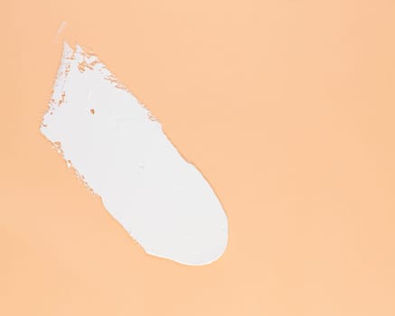 Smear of white cream for face and body on a brown background