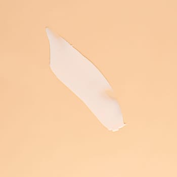 Smear of white cream for face and body on a brown background