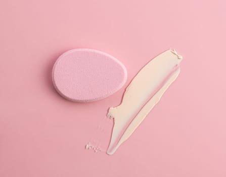 Cosmetic sponge in the shape of an egg on a pink background. Top view