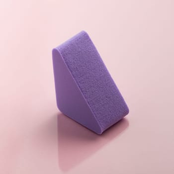 Purple cosmetic sponge on pink background