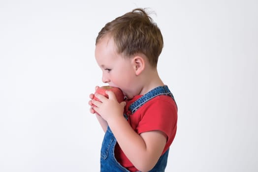 portrait of a girl eating red apple isolated on white. Healthy nutrition. free space.