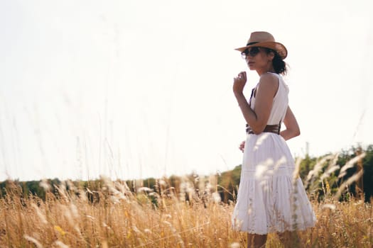 Beautiful girl in a linen dress in a wheat field. Summer vacation, traveling. Bohemian, modern hippie style.