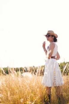 Beautiful girl in a linen dress in a wheat field. Summer vacation, traveling. Bohemian, modern hippie style.