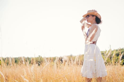 Beautiful girl in a linen dress in a wheat field. Summer vacation, traveling. Bohemian, modern hippie style.