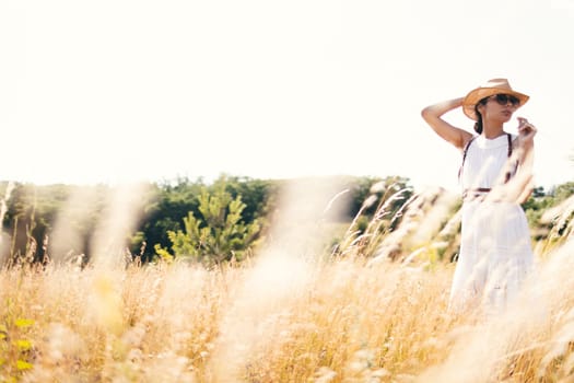 Beautiful girl in a linen dress in a wheat field. Summer vacation, traveling. Bohemian, modern hippie style.