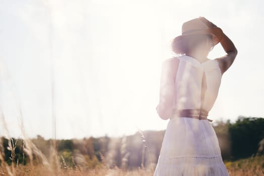 Beautiful girl in a linen dress in a wheat field. Summer vacation, traveling. Bohemian, modern hippie style.