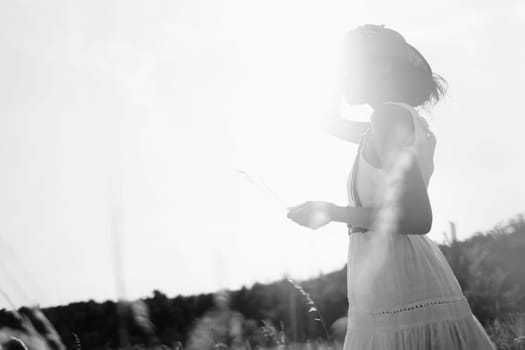 Spirit of freedom. An attractive boho girl in blouse, hat and sunglasses standing on the field on the background of a blue sky. Summer vacation, traveling. Bohemian, modern hippie style