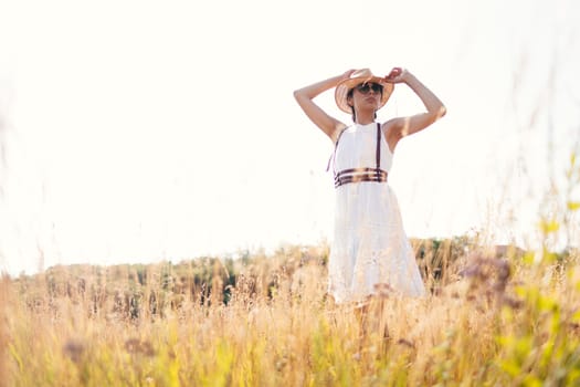 Beautiful girl in a linen dress in a wheat field. Summer vacation, traveling. Bohemian, modern hippie style.