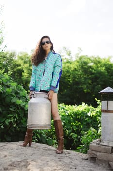 Young fashionable farmer woman posing on camera while holding milk can