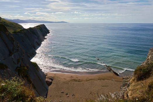 Rock formations on the coast of Zumaya, Spain.Sunny day, empty beach, cottage, boat sl clouds, vegetation. Flysch. San Telmo Chapel