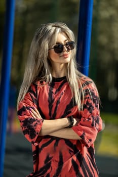 blonde athletic girl stands on the sports ground in a t-shirt, breeches, white sneakers and white headphones