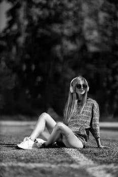 blonde athletic girl sitting on the football field black and white