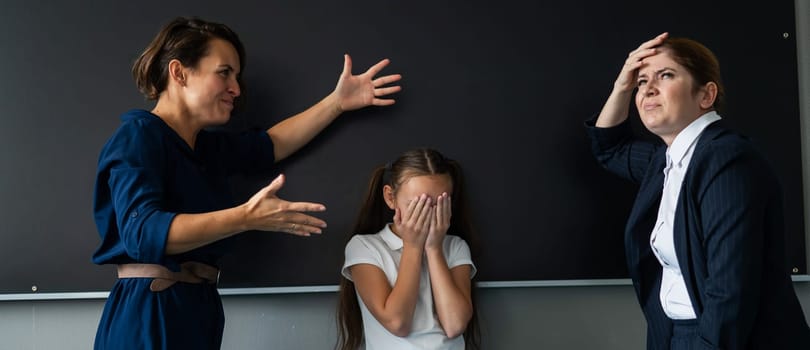 Schoolgirl and her mother yell at the teacher standing at the blackboard