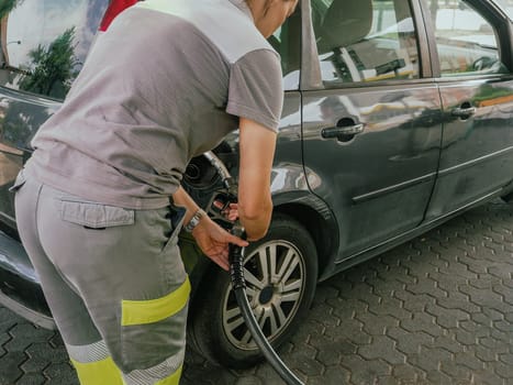 unrecognizable caucasian attendant woman at city fuel station service refuel pump petrol or diesel to a customer car