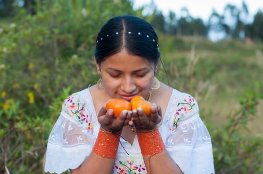 indigenous woman making an offering of some tangerines in a ceremony and ritual in nature. High quality photo