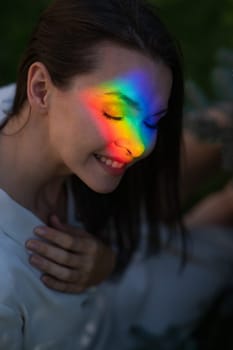 Portrait of caucasian woman with rainbow beam on her face outdoors