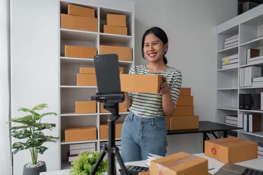 Female online seller is using smartphone to broadcast live on Vlog and talking with customer to selling online product on social media.