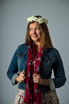 Forty year old woman, wearing bohemian style clothing and a flower crown, with angry expression, isolated on a white background