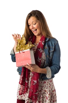 Forty year old woman, wearing bohemian style clothing, opening a gift bag, isolated on a white background