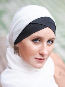 Portrait of a young blue-eyed woman in a hijab outdoors