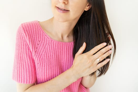 Beautiful brunette girl applies oil on her hair for hair care, vitamins, natural hair oils