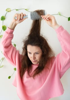 The girl dries her hair on a brush. Hair care. The concept of home care, drying healthy hair with a hair dryer and brush