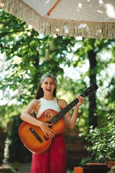 Happy hippie girl is having a good time with playing on guitar in camper trailer. Holiday, vacation, trip concept.High quality photo