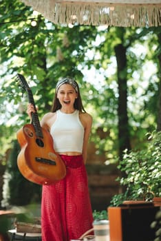 Happy hippie girl is having a good time with playing on guitar in camper trailer. Holiday, vacation, trip concept.High quality photo