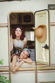 Happy hippie friends are having a good time together in a camper trailer. Holiday, vacation, trip concept. High quality photo