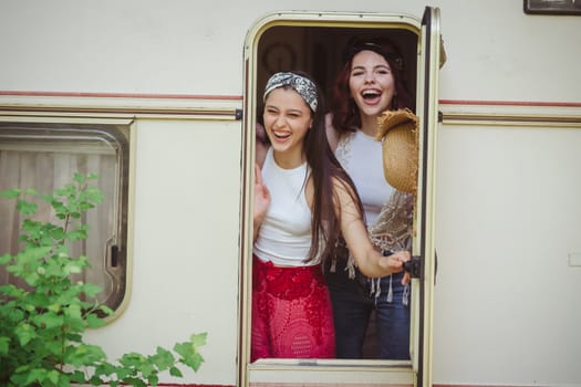 Happy hippie friends are having a good time together in camper trailer. Holiday, vacation, trip concept. High quality photo