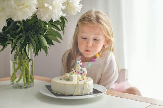 A girl of four years old making wish blowing candles on a cake