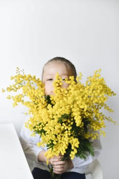 A girl holding mimosa on a white wall background