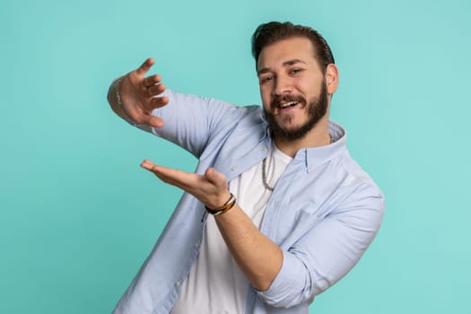 Young lebanese man showing wasting, throwing money around, more tips, big profit, winning lottery jackpot, successful shopping payment purchase cashback. Arabian guy isolated on studio blue background