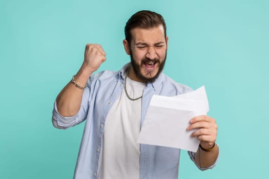 Handsome lebanese man open envelope take out letter reads it feel happy. Arabian guy career growth advance promotion, bank loan approve, monetary award, long-awaited invitation great news, lottery win