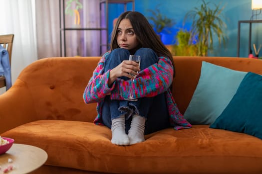 Sad young woman girl sitting at home looks pensive of unrequited love, suffers from unfair situation, drinking champagne, bad news. Problem break up, depressed feeling bad annoyed, burnout, bankruptcy
