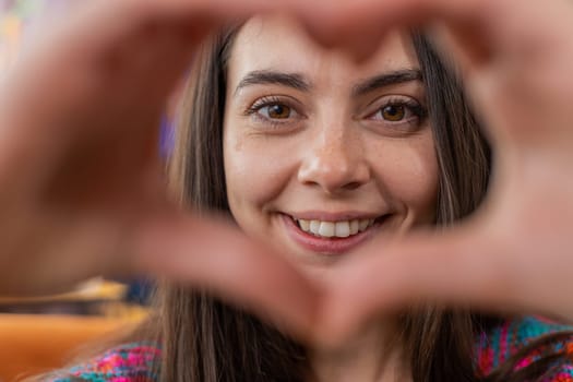 I love you. Happy Caucasian woman at home living room couch makes symbol of love, showing heart sign to camera express romantic feelings express sincere positive feelings. Charity, gratitude, donation