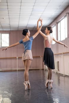 Two Asian ballerinas are dancing in the class