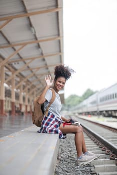 Young woman female smiling traveler with back pack looking to map while waiting for the train at train station. High quality photo..