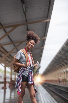 Young woman female smiling traveler with back pack looking to map while waiting for the train at train station. High quality photo..