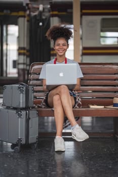 Young woman girl female sitting use computer laptop and travel bag suit case on the floor at station..