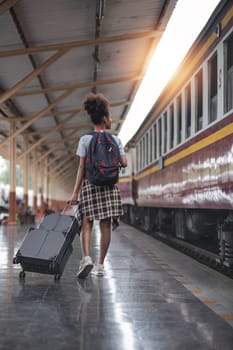 Young female traveler walking standing with a suitcase at train station. woman traveler tourist walking standing smiling with luggage at train station..